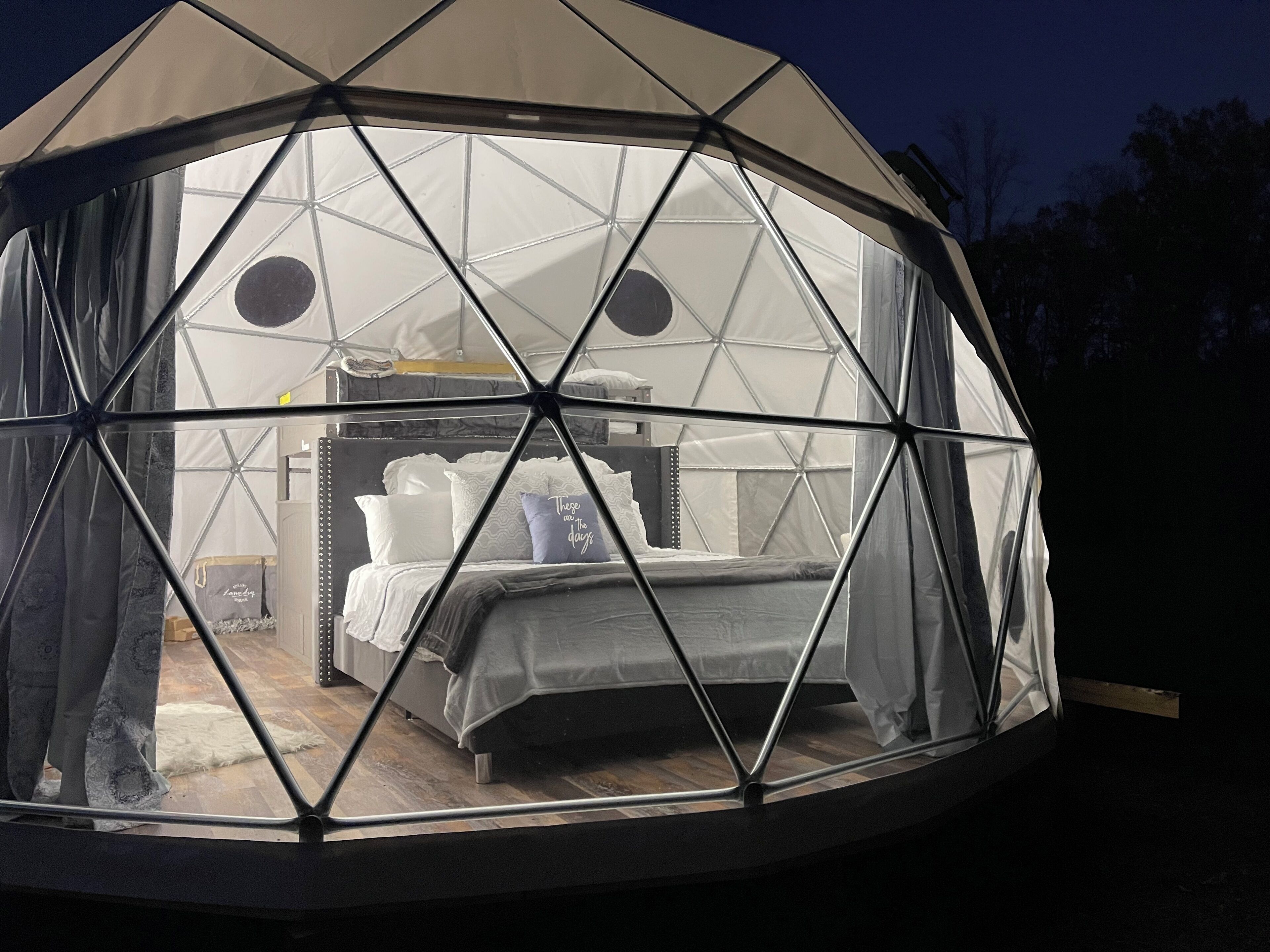 Une structure en forme de dôme géodésique, avec un lit et une armoire à l’intérieur.
