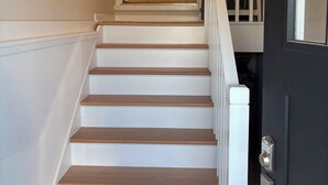 A staircase with white walls and wooden steps leading to a landing.