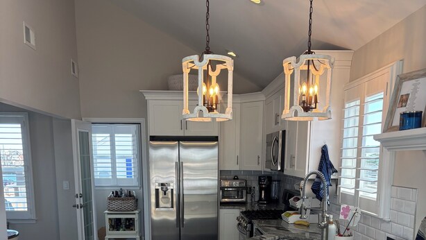 A modern kitchen with a central island, stainless steel appliances, and a dining area with wicker chairs.