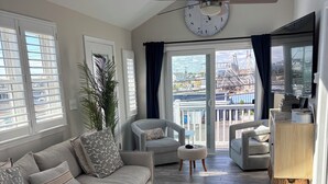 A spacious living room with a large window, a ceiling fan, and a view of a marina.