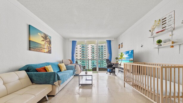 A modern living room with a beige sofa, a coffee table, and a wooden crib. - Beachfront Ocean View Balcony Pool Gym (Hollywood)