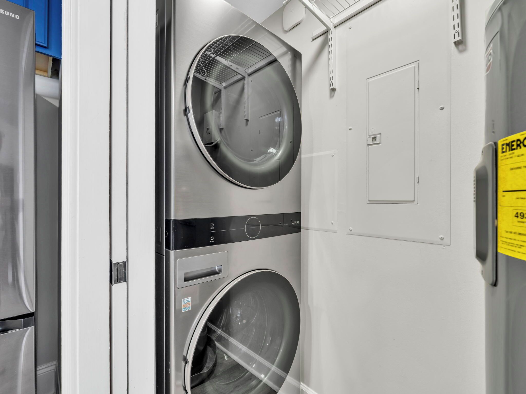 Une buanderie équipée de deux machines à laver, d’un sèche-linge et d’un panneau de commande.