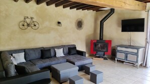 Un salon comprenant un canapé, des poufs, une cheminée, un téléviseur et une décoration murale représentant un vélo.
