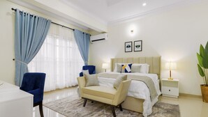 Una habitación de hotel moderna con una cama, un escritorio, una silla y una mesita de noche con lámpara.