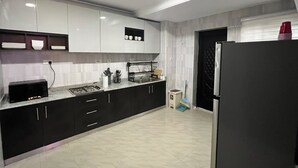 Una cocina moderna con armarios blancos, un refrigerador negro y una estufa a gas.