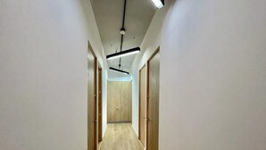 Un pasillo estrecho con puertas de madera a ambos lados y piso de color claro.