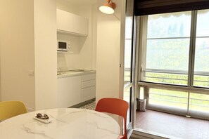 Une cuisine moderne avec des meubles blancs, un four à micro-ondes et un coin repas comprenant une table et des chaises en marbre.