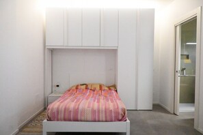 A bedroom with a bed, a nightstand, a wardrobe, and a bathroom with a glass door. - SE193 – Senigallia, brand-new studio with air conditioning (Senigallia)