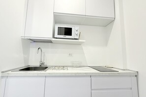 A modern kitchen with white cabinetry, a built-in microwave, a stainless steel sink, and a glass bowl on the countertop. - SE193 – Senigallia, brand-new studio with air conditioning (Senigallia)