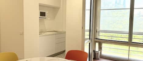 Una cocina moderna con armarios blancos, un microondas y un comedor con una mesa y sillas de mármol.