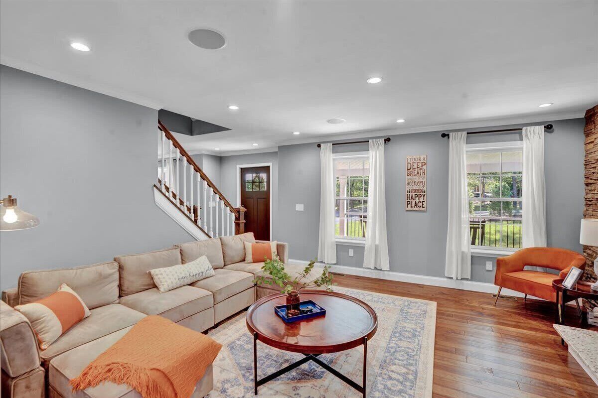 A living room with a beige sofa, a round coffee table, and a staircase.
