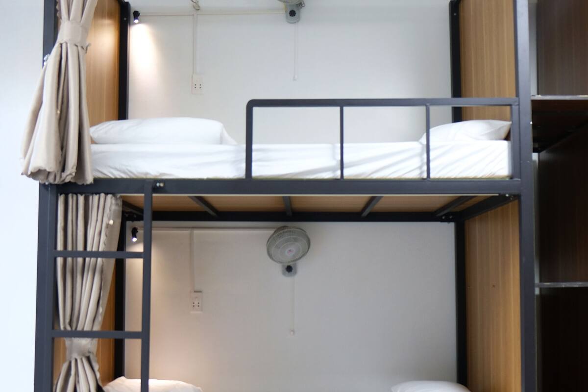 A bunk bed with two levels, each with a pillow and a rolled towel.