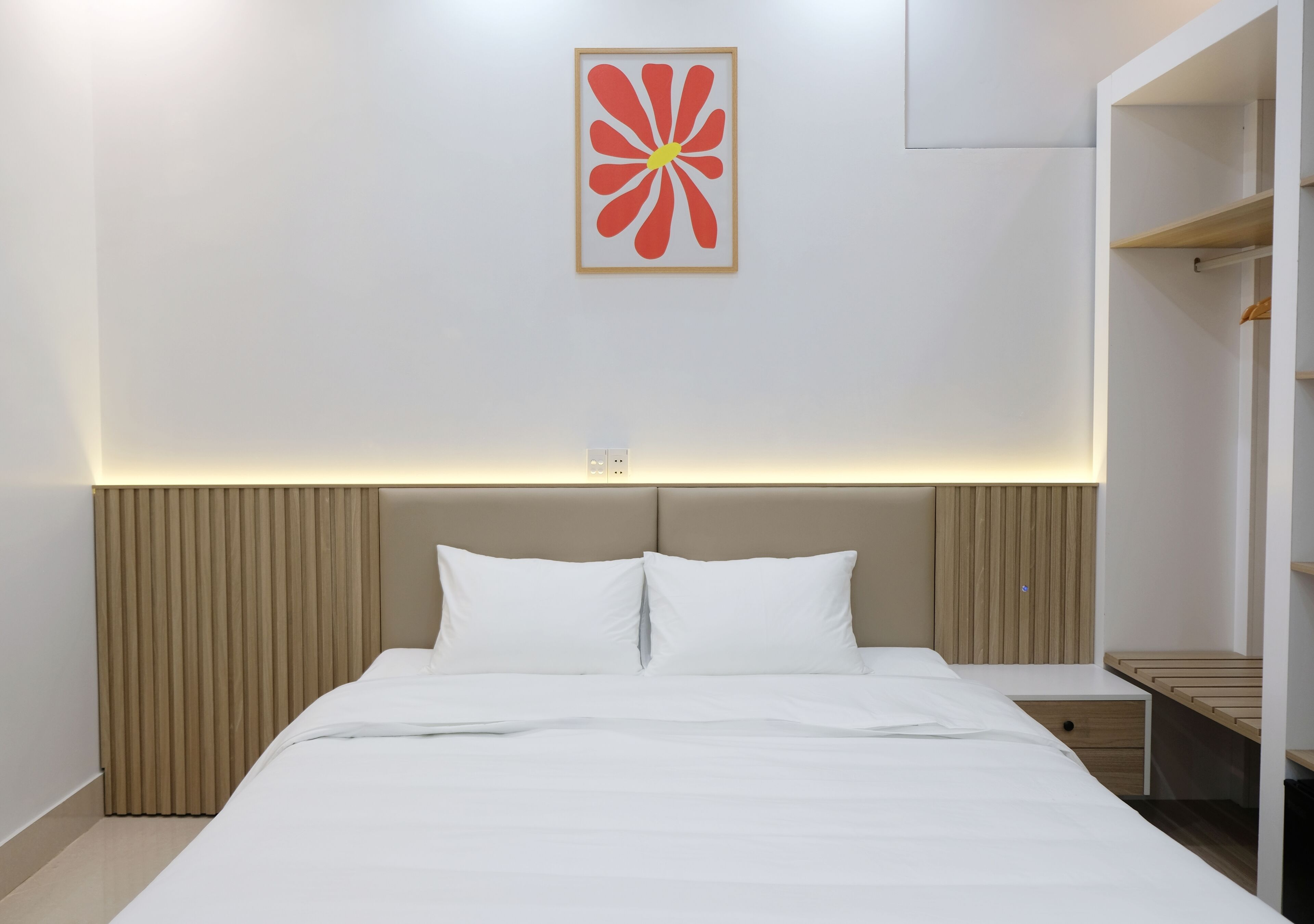 Una habitación de hotel moderna con una cama grande, un cabecero con listones verticales, una mesita de noche y un armario con espejo.