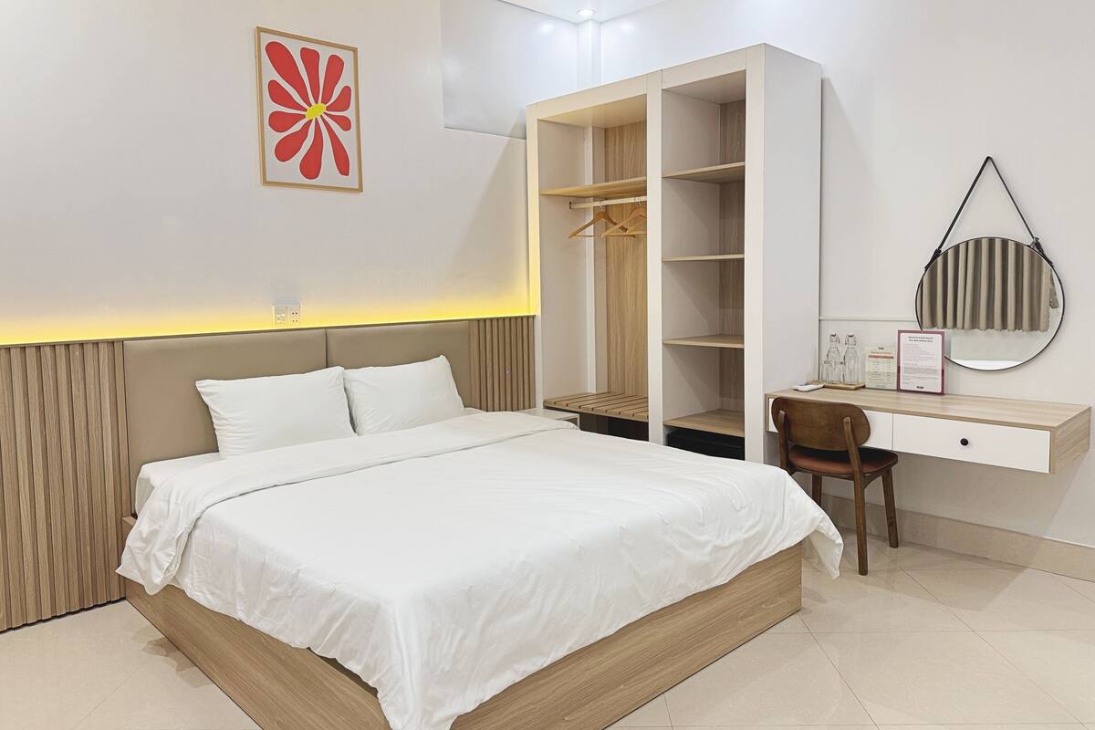 A modern bedroom with a bed, a wardrobe, a desk, and a mirror.
