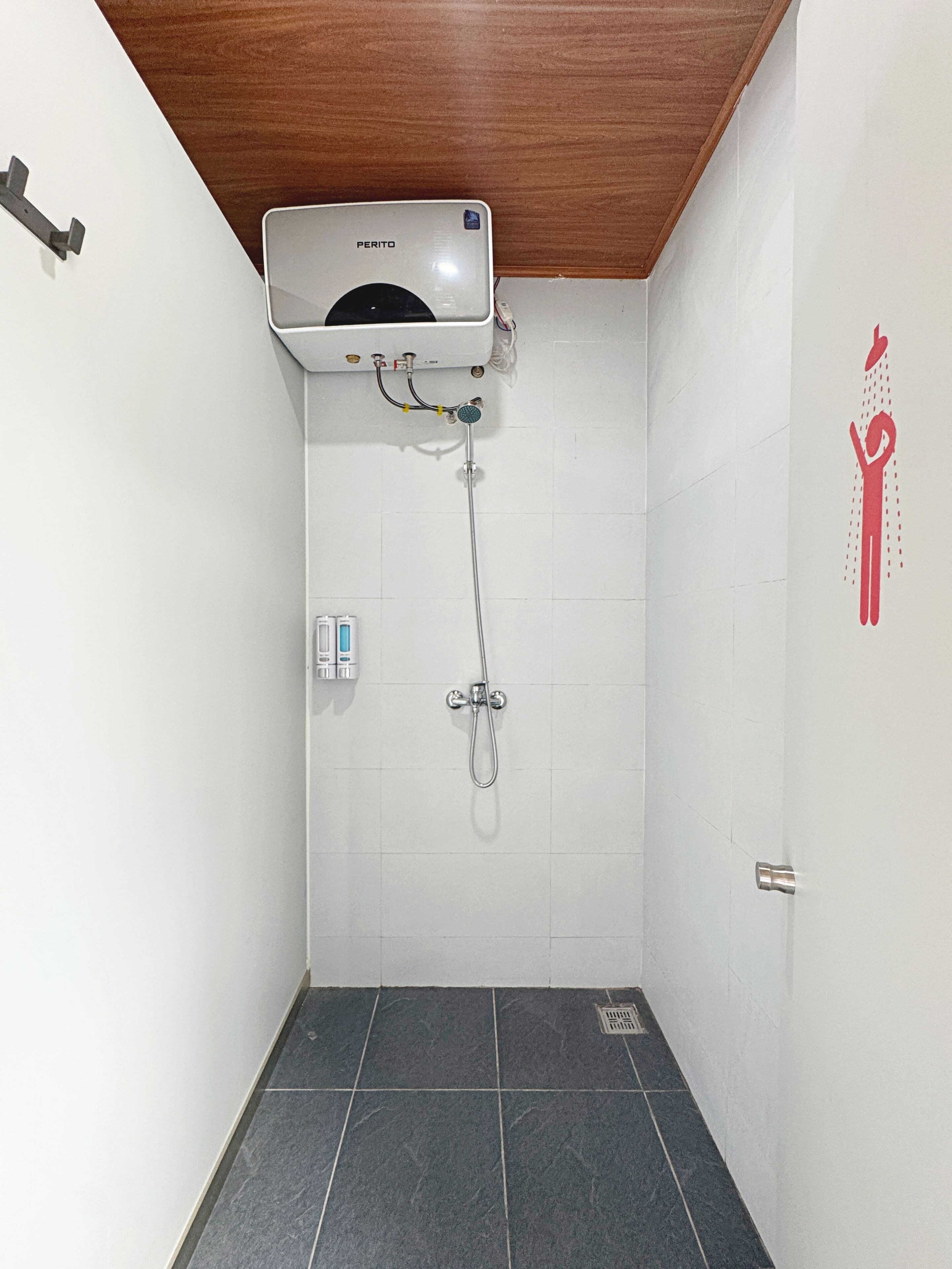 A shower area with a wall-mounted heater, a handheld showerhead, and a hand dryer.