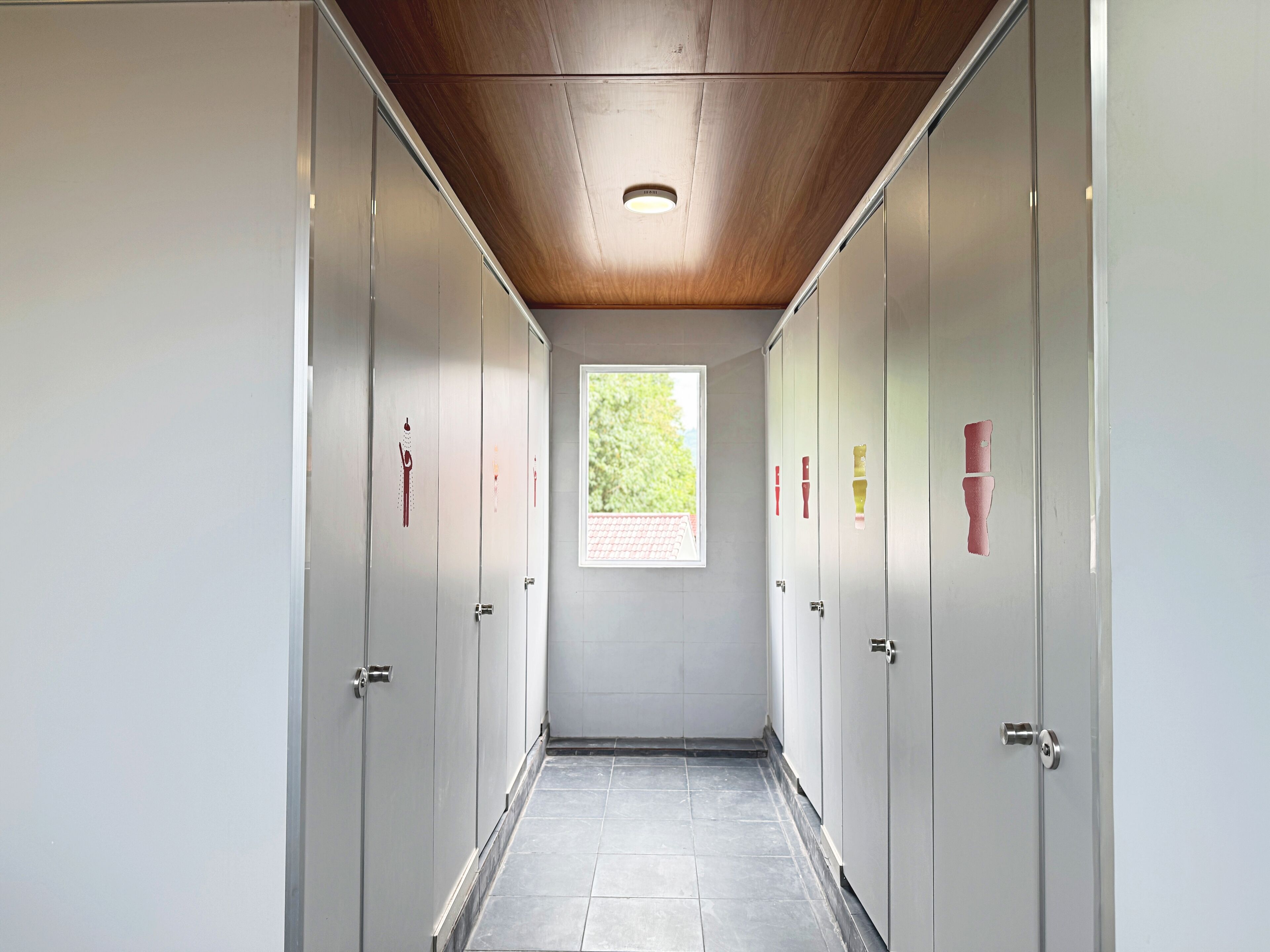 A corridor with lockers, a wooden ceiling, and a window with a view of greenery.