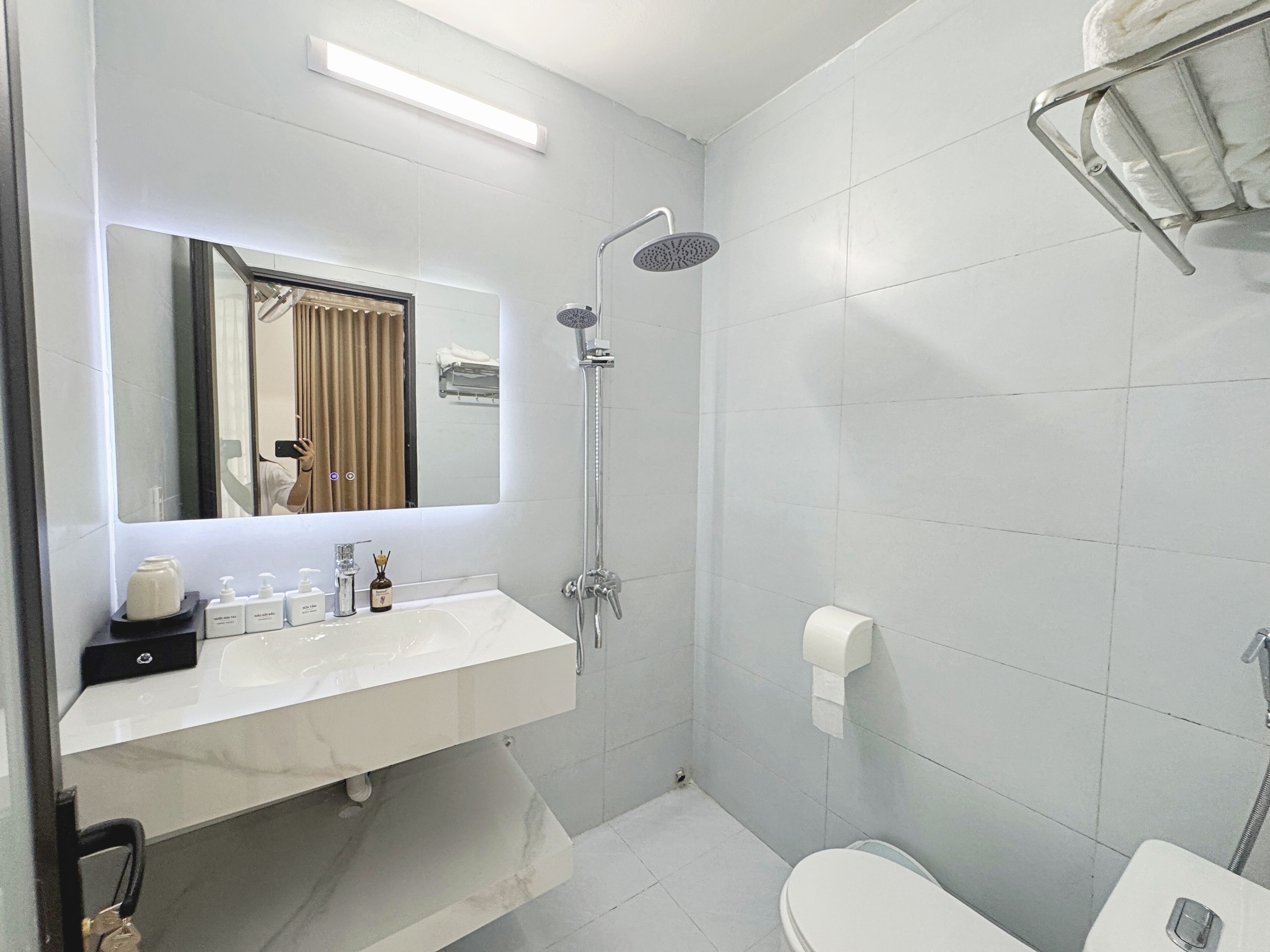 A modern bathroom with a white sink, mirror, and shower.