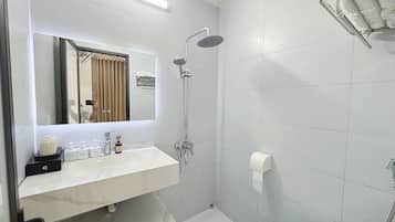 A modern bathroom with a white sink, mirror, and shower.