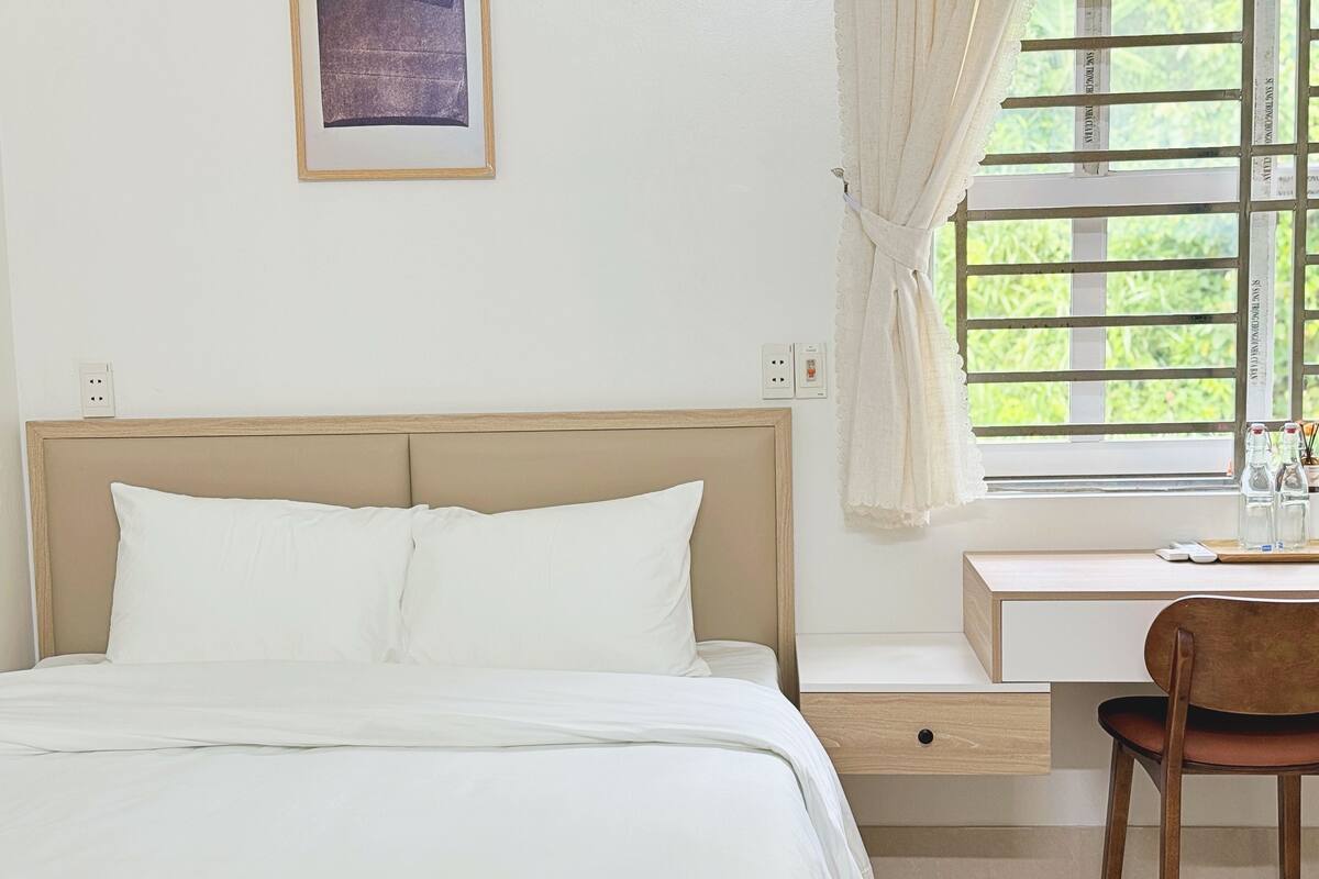 A bedroom with a bed, a desk, and a chair.