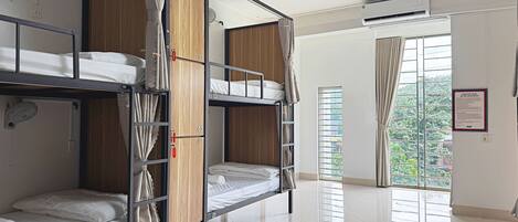 A bunk room with bunk beds, a ceiling fan, an air conditioning unit, and a window with blinds.
