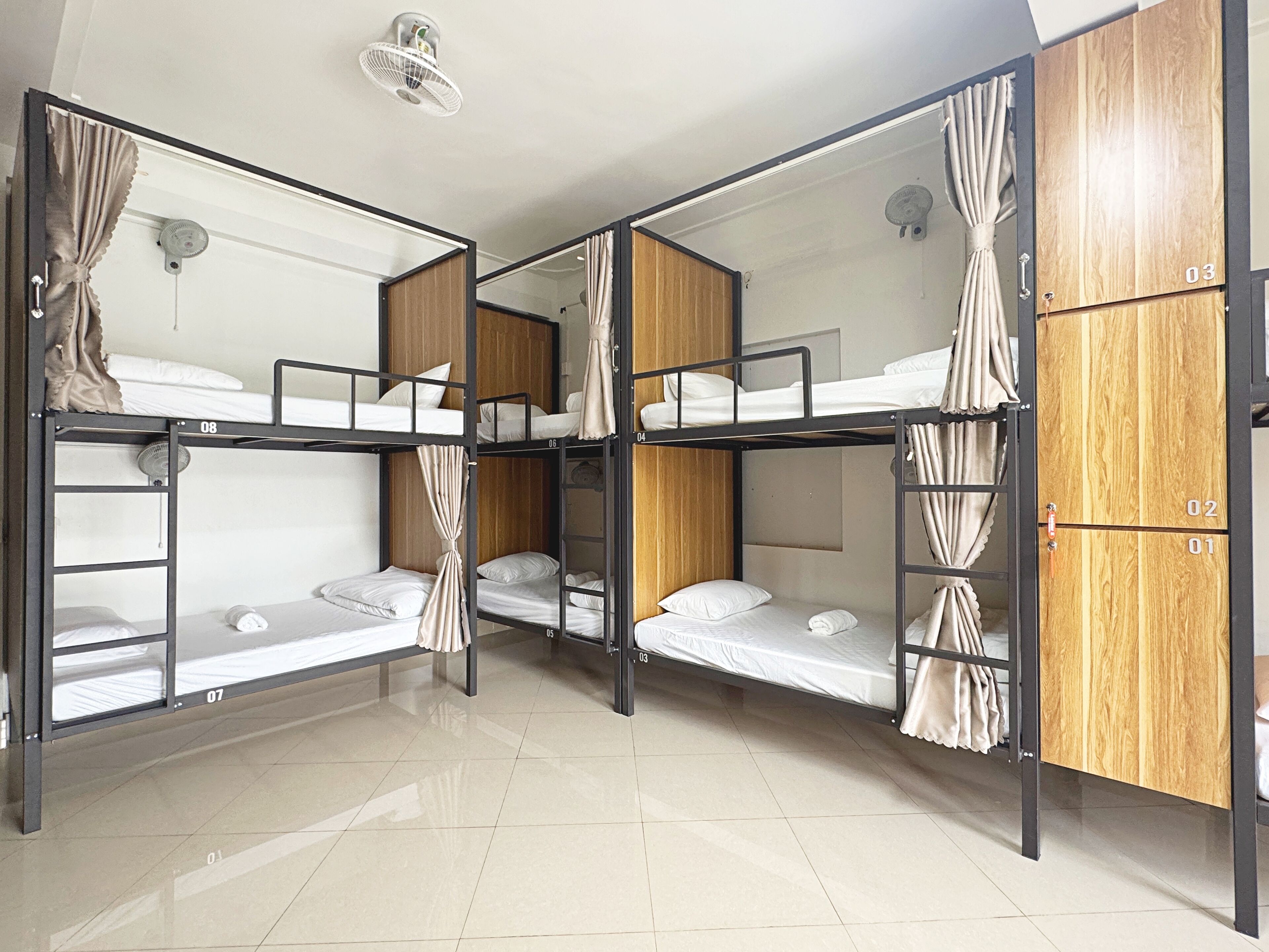 A room with bunk beds, wooden wardrobe, and a ceiling fan.