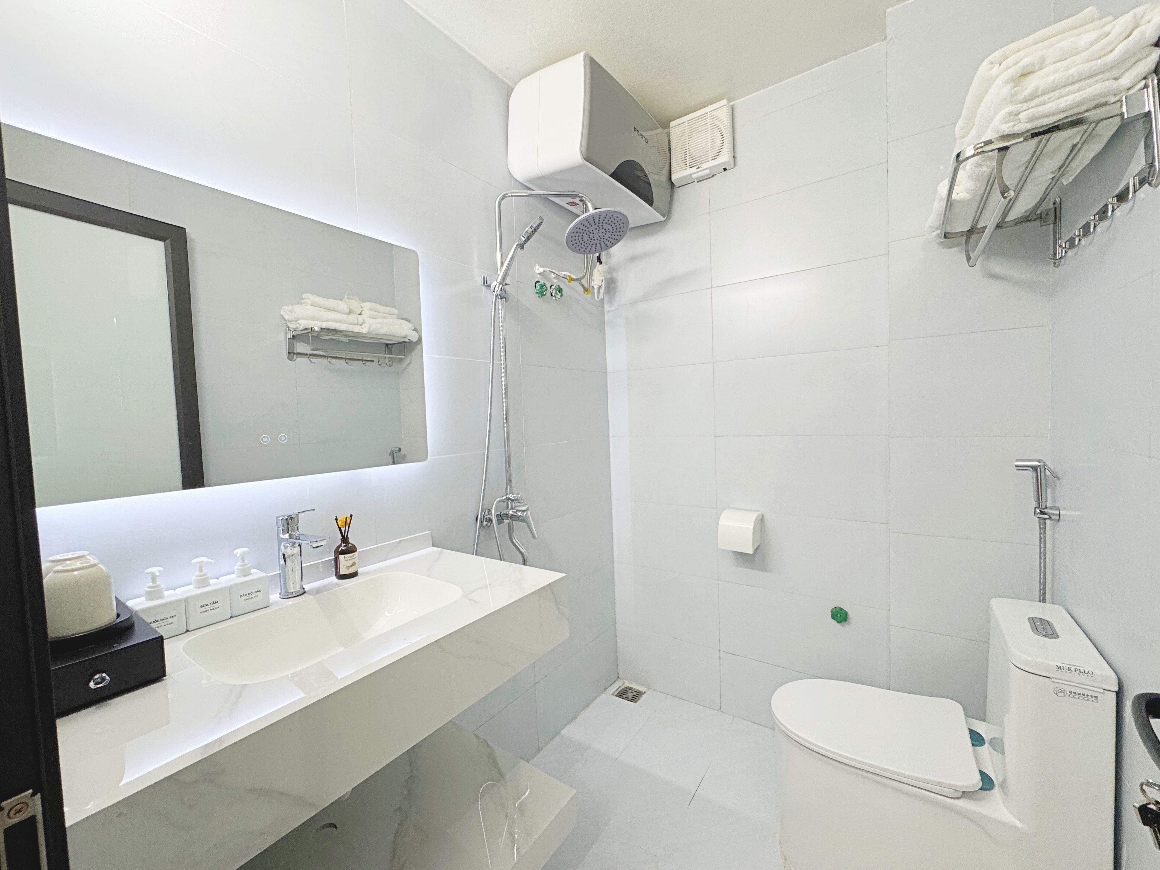 A modern bathroom with a dual sink vanity, a large mirror, a shower with a handheld showerhead, and a toilet.