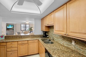 A kitchen with wooden cabinets, granite countertops, and a tiled backsplash.