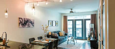 A modern living room with a dining area, a sofa, and a ceiling fan.