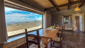 Un coin repas rustique avec une table et des chaises en bois, un mur en pierre et une vue sur la campagne.