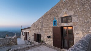 Un bâtiment en pierre orné d’une croix bleue et du chiffre 1861, avec une porte et une fenêtre d’où l’on peut admirer le coucher de soleil.