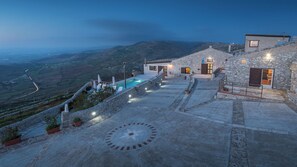 Un bâtiment en pierre doté d’une piscine et d’un espace extérieur aménagé, offrant une vue sur une vallée.