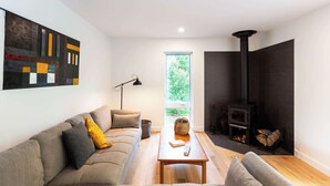 Ein modernes Wohnzimmer mit einer Couch, einem Tisch, einer Stehlampe, einem Kamin und einem großen Fenster.
