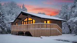 Eine Holzhütte mit Balkon, umgeben von schneebedeckten Bäumen.