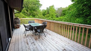 Eine Holzterrasse mit Tisch und Stühlen mit Blick auf einen bewaldeten Bereich.
