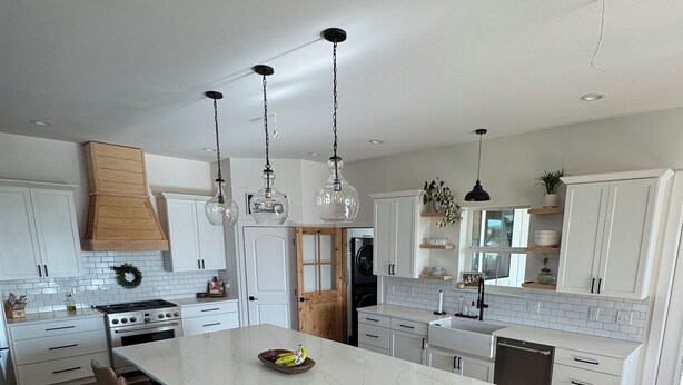 A modern kitchen with a large island, white cabinetry, and pendant lighting. - Spacious 6 bedroom home with theater room and gym just minutes from Yakima! (Selah)