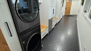A modern laundry room with a large LG washer and dryer, white cabinetry, and a herringbone-patterned floor. - Spacious 6 bedroom home with theater room and gym just minutes from Yakima! (Selah)