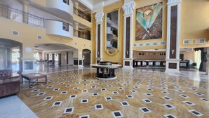 A spacious lobby with a marble floor, a reception desk, and a large painting on the wall.