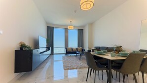 A modern living room with a dining area, large windows, and a view of the sea. - Modern 2BR | 60th Floor Views in Business Bay (دبي)