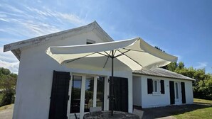 A white building with a covered patio area, featuring a round table and chairs.