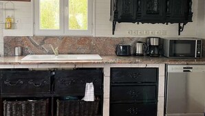 A kitchen with dark wooden cabinets, a granite countertop, a sink, a coffee maker, a microwave, and a dishwasher.
