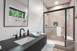 Une salle de bain moderne avec un grand lavabo, des toilettes et une douche à parois de verre.