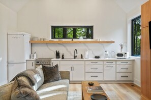 A compact kitchen with white cabinetry, a built-in microwave, and a window above the sink.