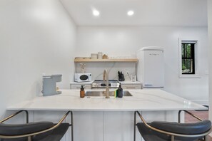 Una cocina moderna con una isla central, armarios blancos y un microondas integrado.