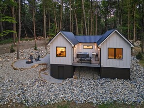 A cabin with a deck, a hot tub, and a fire pit.