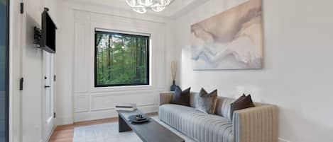 A modern living room with a sofa, a coffee table, and a large window.