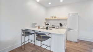 A modern kitchen with a central island, bar stools, a refrigerator, and built-in appliances. - The U Haus | Hocking Hills, Modern & New, Hot Tub (Rockbridge)