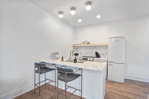 Una cocina moderna con una isla central, taburetes de bar, refrigerador y electrodomésticos integrados.