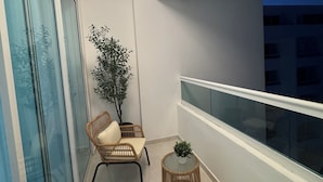 A balcony with wicker chairs, a small table, and a potted plant. - 3 bedrooms, 4 bathrooms, private pool and much more. (Playa Juan Dolio)
