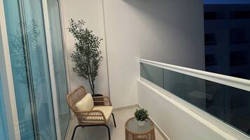 A balcony with wicker chairs, a small table, and a potted plant.