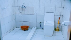 A small bathroom with white tiles, a shower, a toilet, a sink, and a broom. - Peaceful apartment with WiFi in charming Musanze-down town. (Musanze)